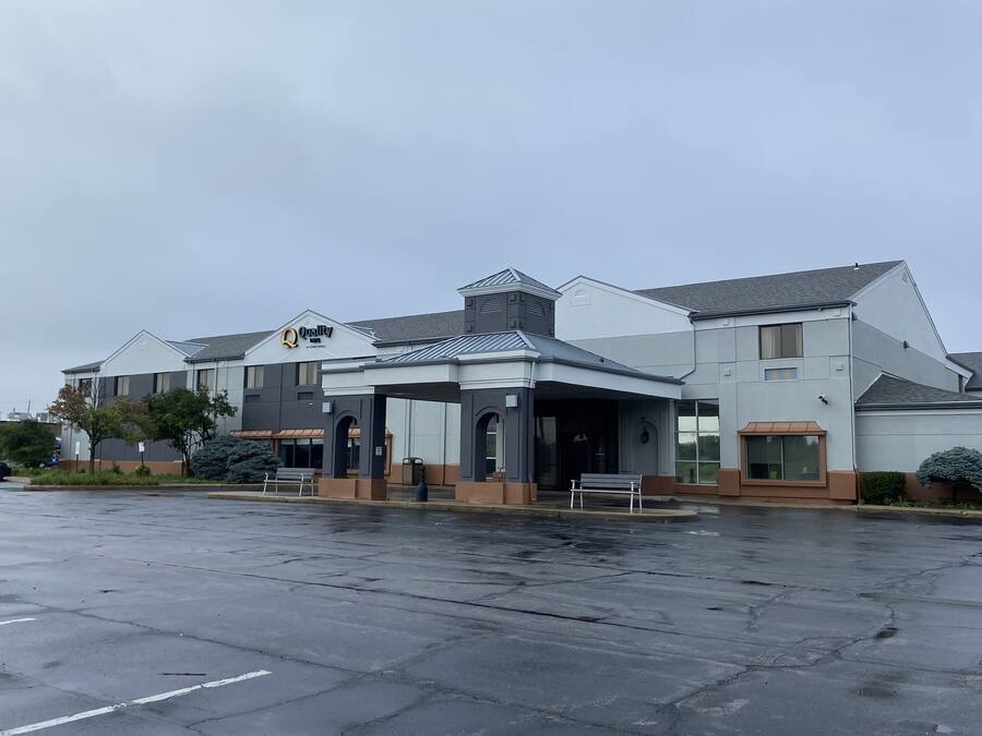 Un hotel moderno con entrada cubierta, varios pisos y estacionamiento.
