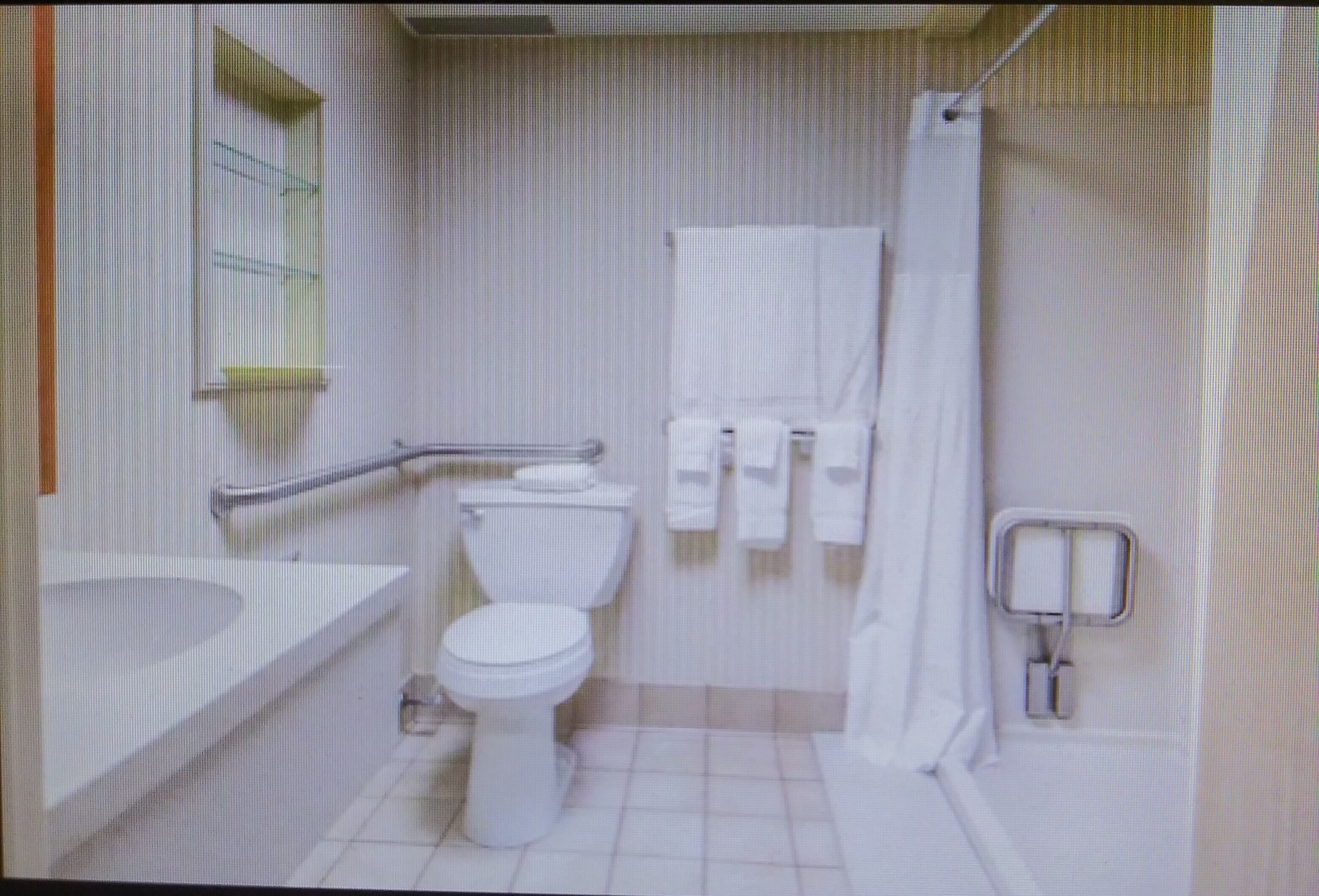 A small, white bathroom with a toilet, sink, and shower.