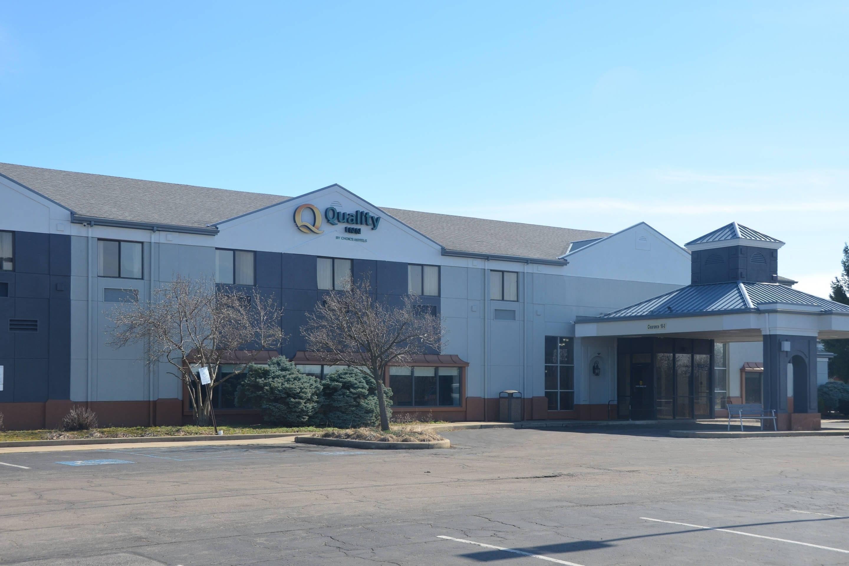 A large, modern building with a prominent 'Quality' sign, a covered entrance, and a parking lot.