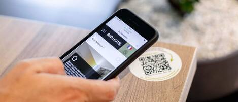 Un teléfono inteligente mostrando una aplicación de reservas de hotel con un código QR sobre una superficie de madera.