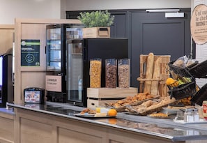 A breakfast buffet with various food items and a refrigerator. - B&B HOTEL Lourdes Centre Gare (Lourdes)