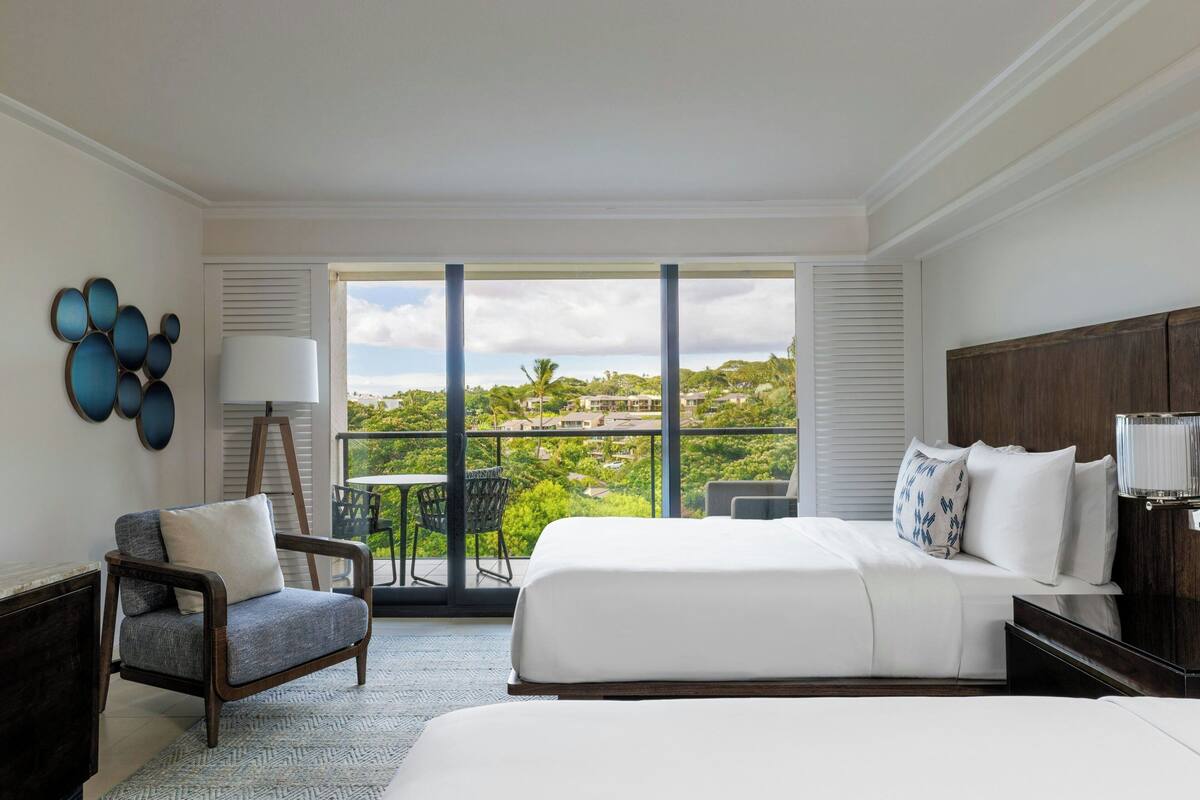 Une chambre d’hôtel avec un grand lit, une chaise, une table et un balcon avec vue.