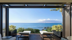 A deck with two lounge chairs facing a scenic ocean view, a wooden floor, and a modern architectural design. - Wailea Beach Resort - Marriott, Maui (Kihei)