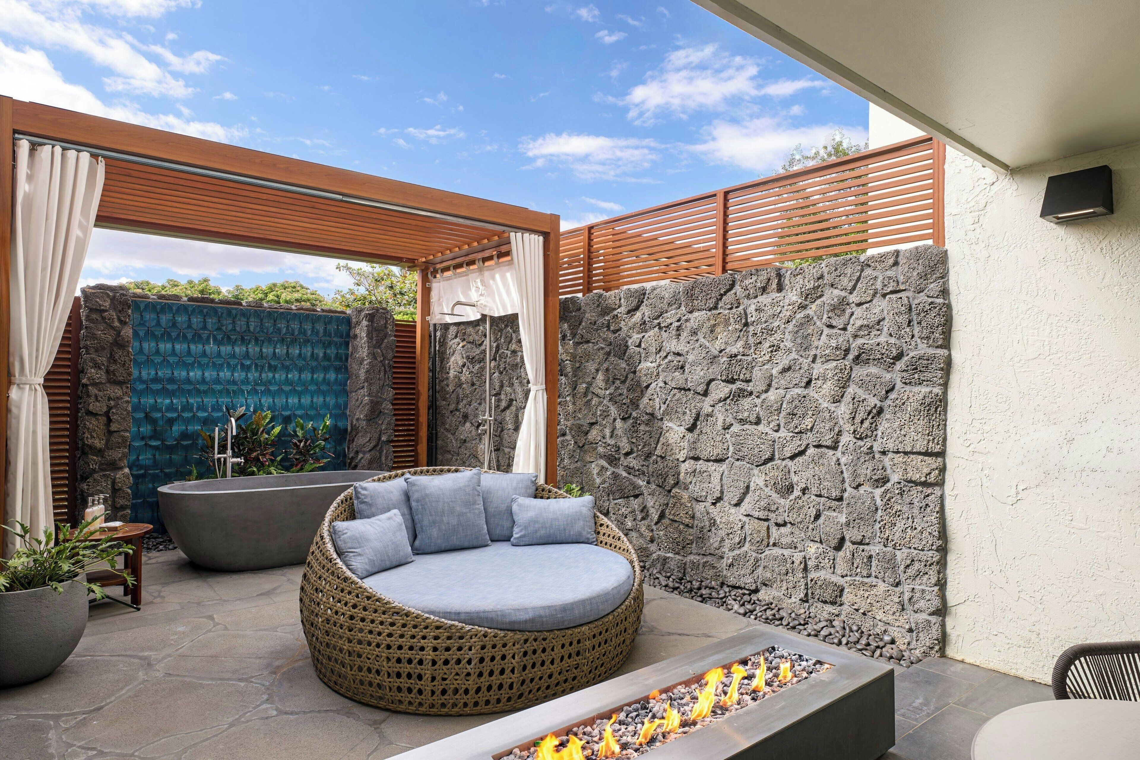 A modern outdoor seating area with a stone wall, a fire feature, and a blue textured wall.