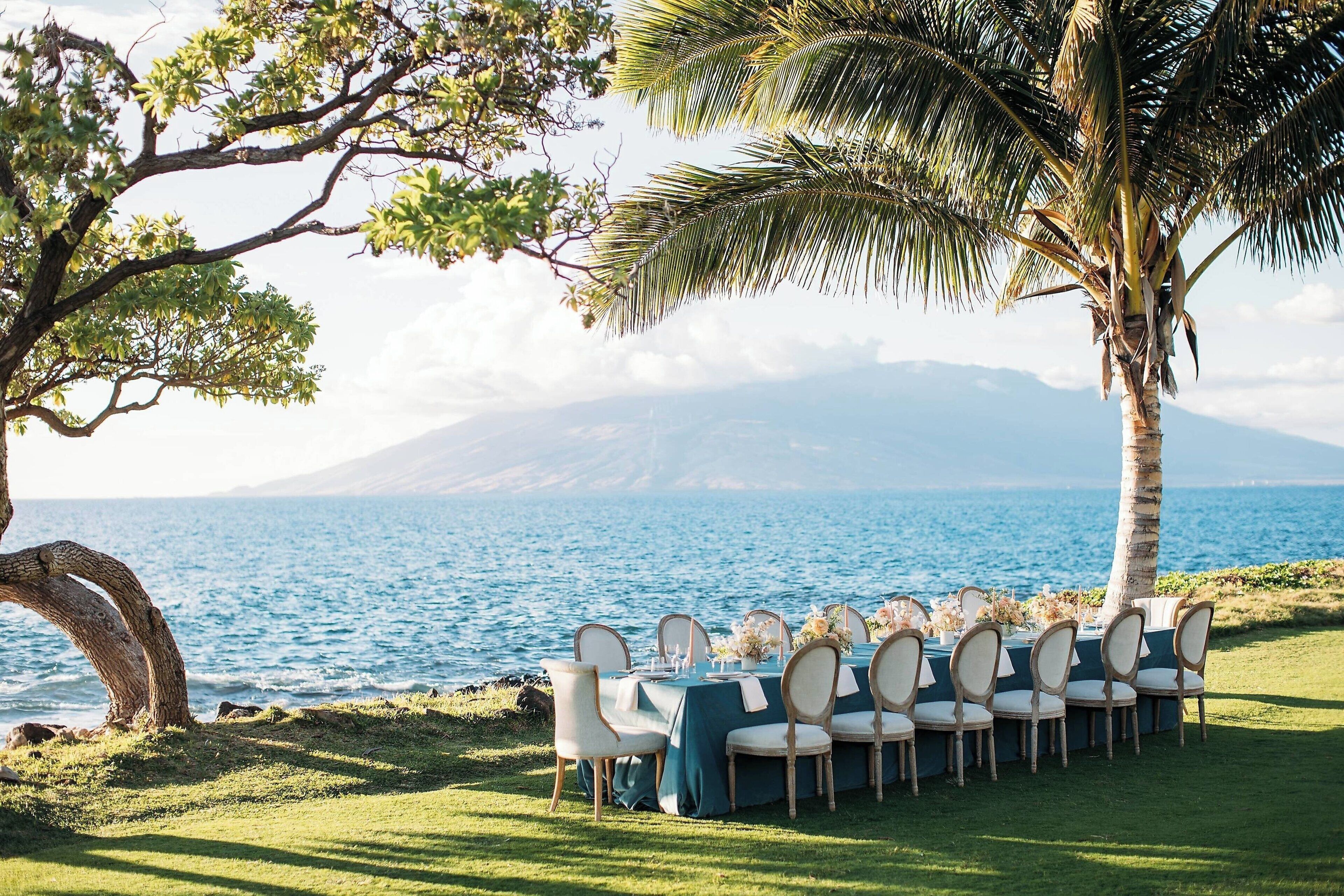 A table set up outdoors with chairs, overlooking a body of water and a mountain in the background.