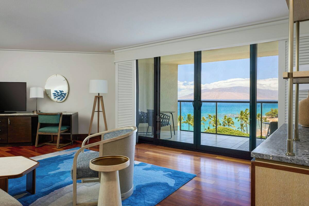 Une chambre d’hôtel dotée d’un grand balcon, d’une télévision, d’un bureau et d’une chaise.