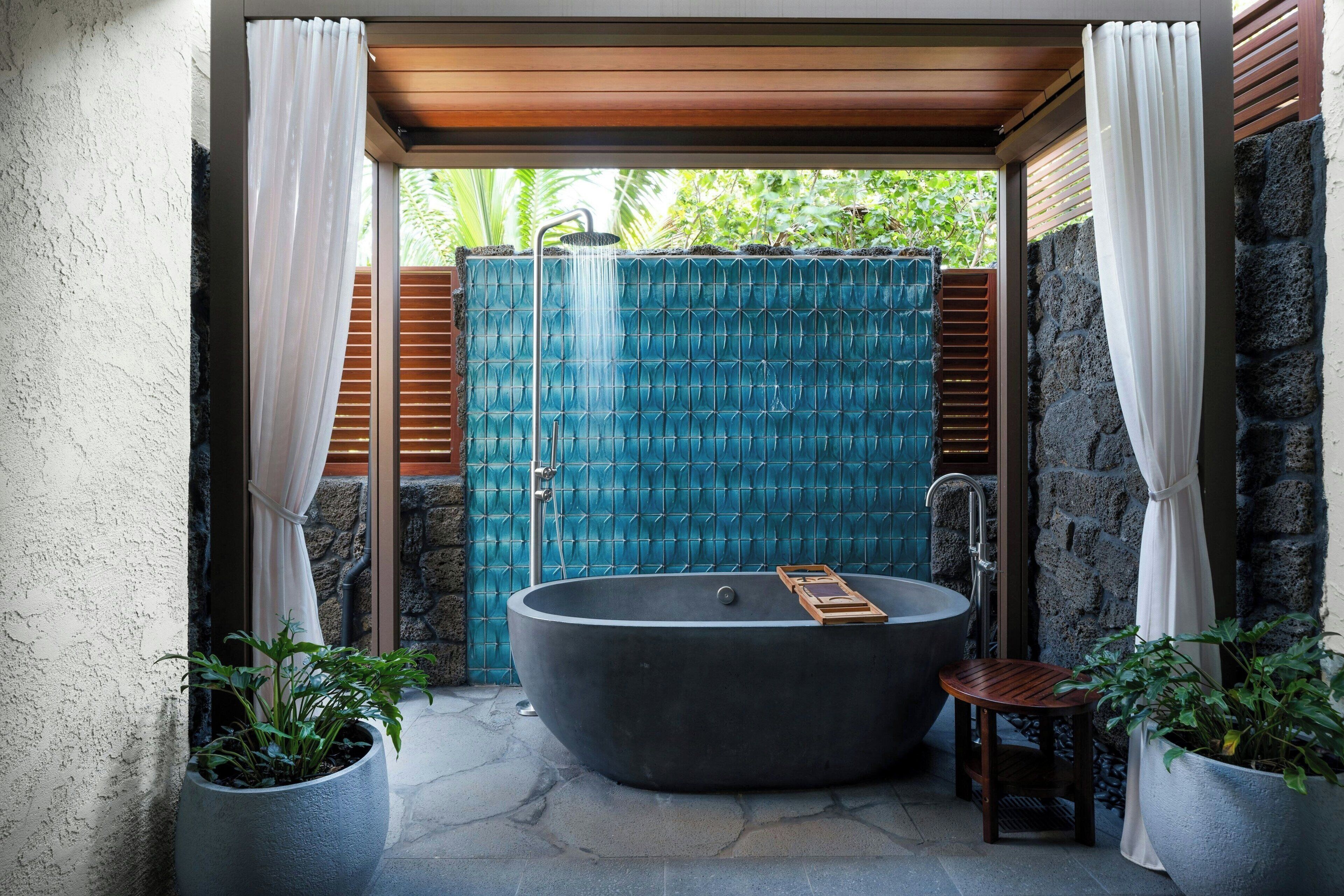 A spa area with a large bathtub, a wooden stool, and potted plants.