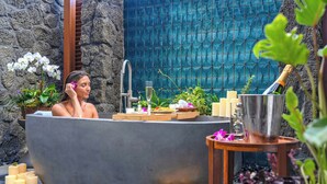 A spa setting with a bathtub, candles, flowers, and a champagne bottle. - Wailea Beach Resort - Marriott, Maui (Kihei)