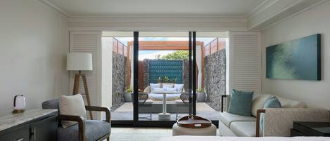Habitación de hotel con cama, escritorio, sillón, sofá y balcón con vistas al exterior.