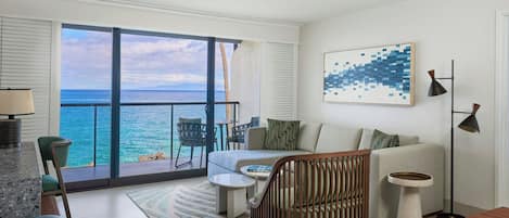 A modern living room with a large window overlooking the ocean, a sofa, a coffee table, and a dining area.