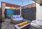 A patio with a round seating area, a fire feature, and a stone wall.