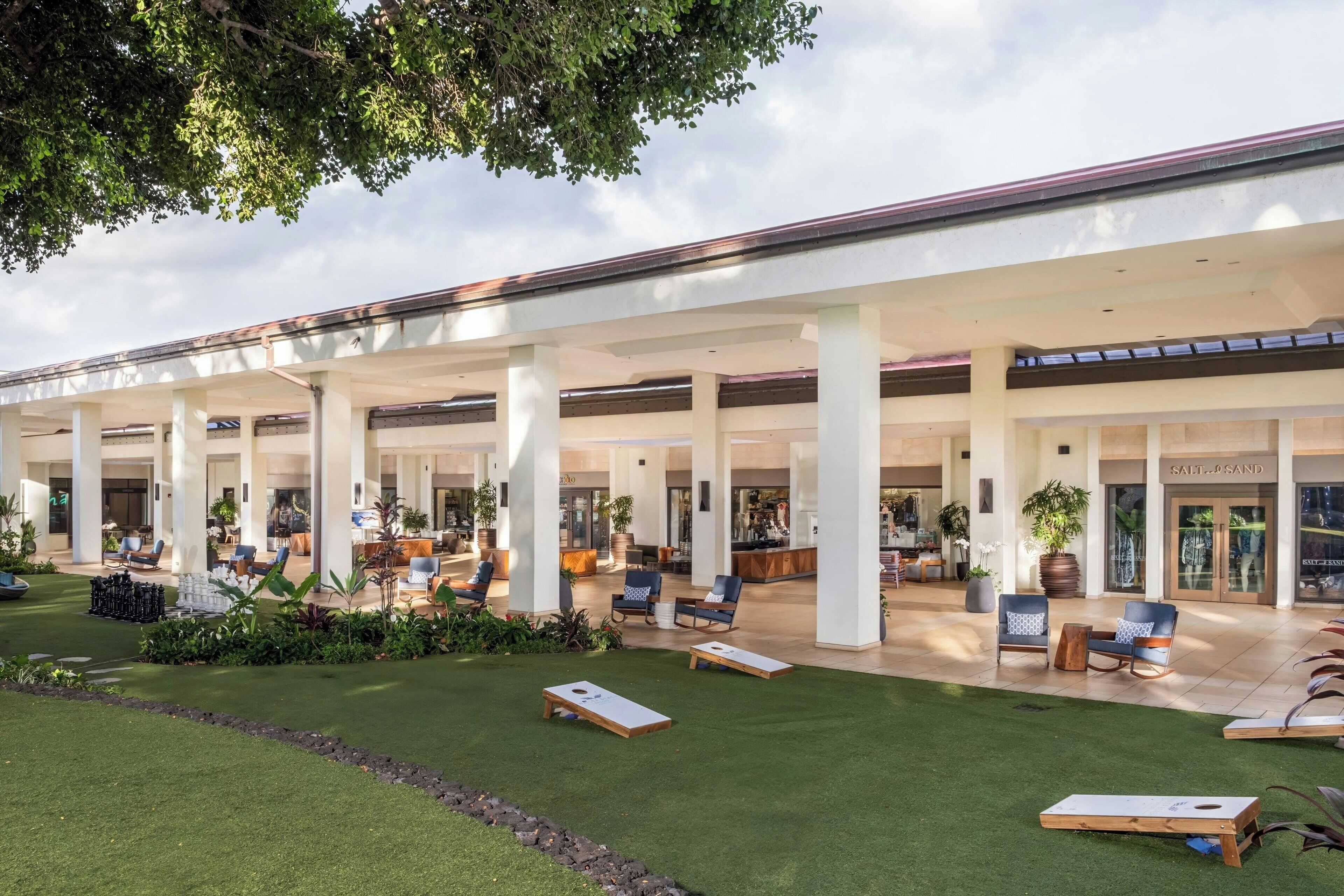 A spacious outdoor area with a covered seating area, artificial grass, and a variety of seating options.