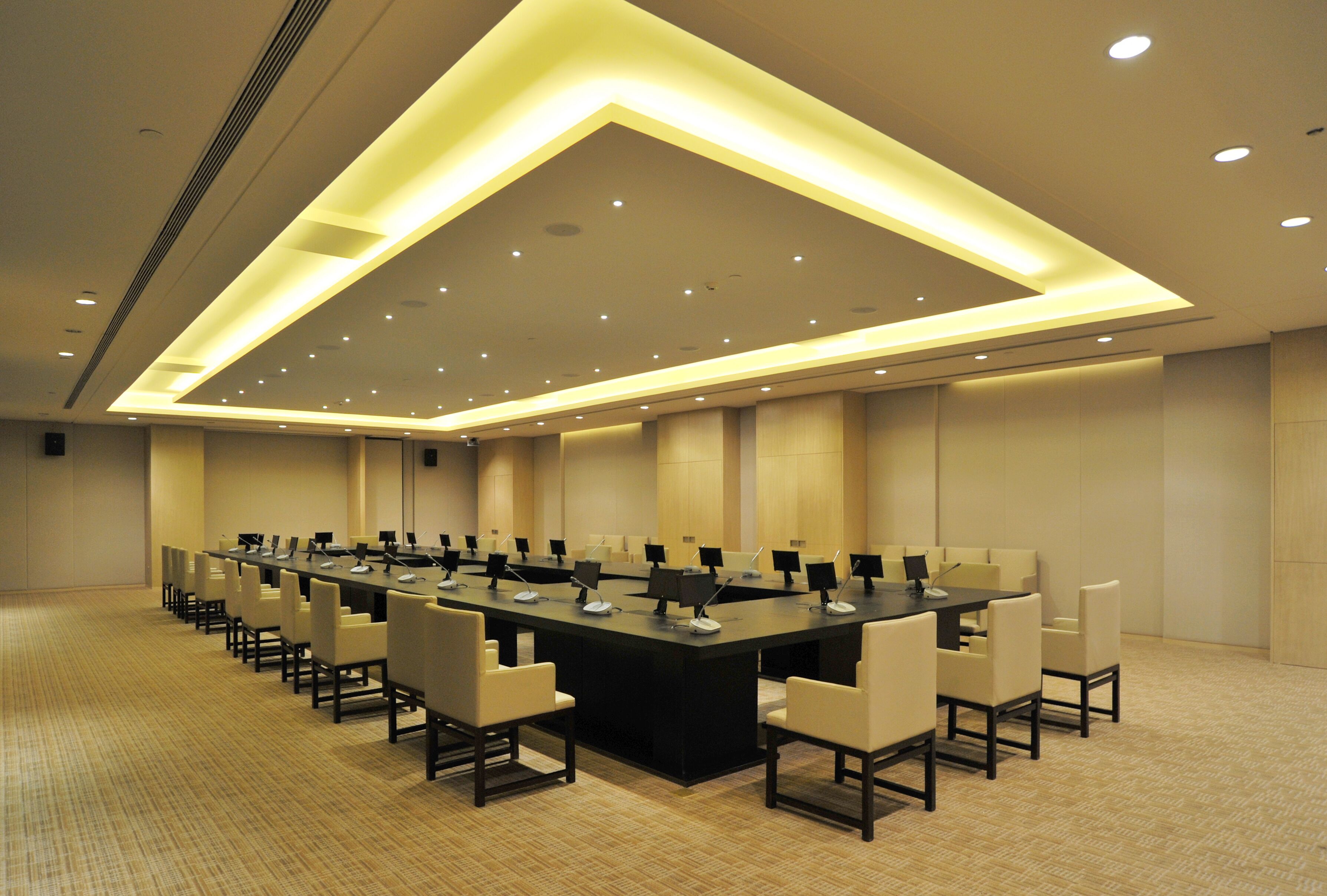 Une salle de conférence dotée d’une longue table, de nombreuses chaises et d’un plafond au design moderne.