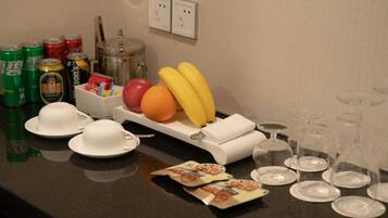 A breakfast setup with plates, cups, a fruit tray, and empty wine glasses.