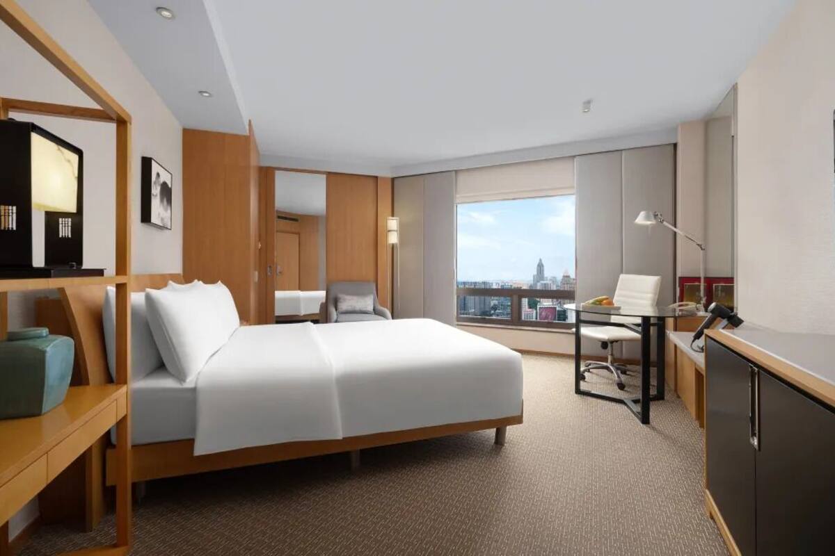 Une chambre d’hôtel moderne dotée d’un grand lit, d’un bureau, d’une chaise et offrant une vue sur la ville.