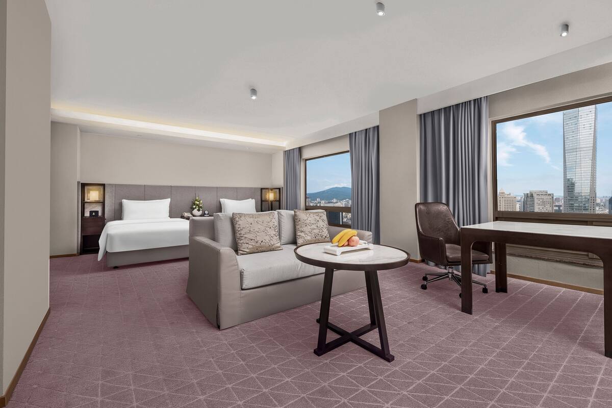 Une chambre d’hôtel avec un lit, un canapé, un bureau et une vue sur la ville.
