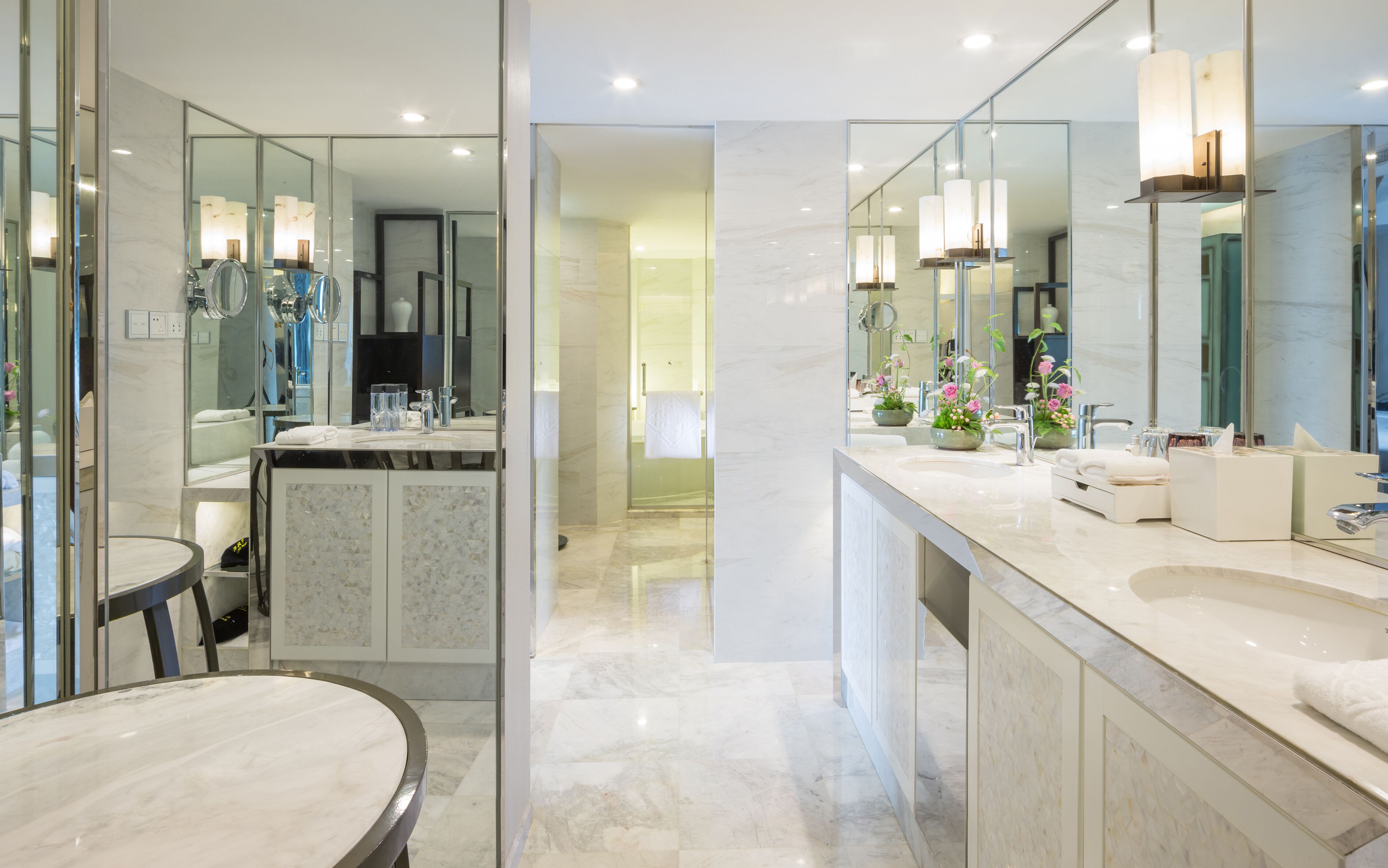 Un baño moderno con un espejo grande, dos lavamanos y piso de mármol.