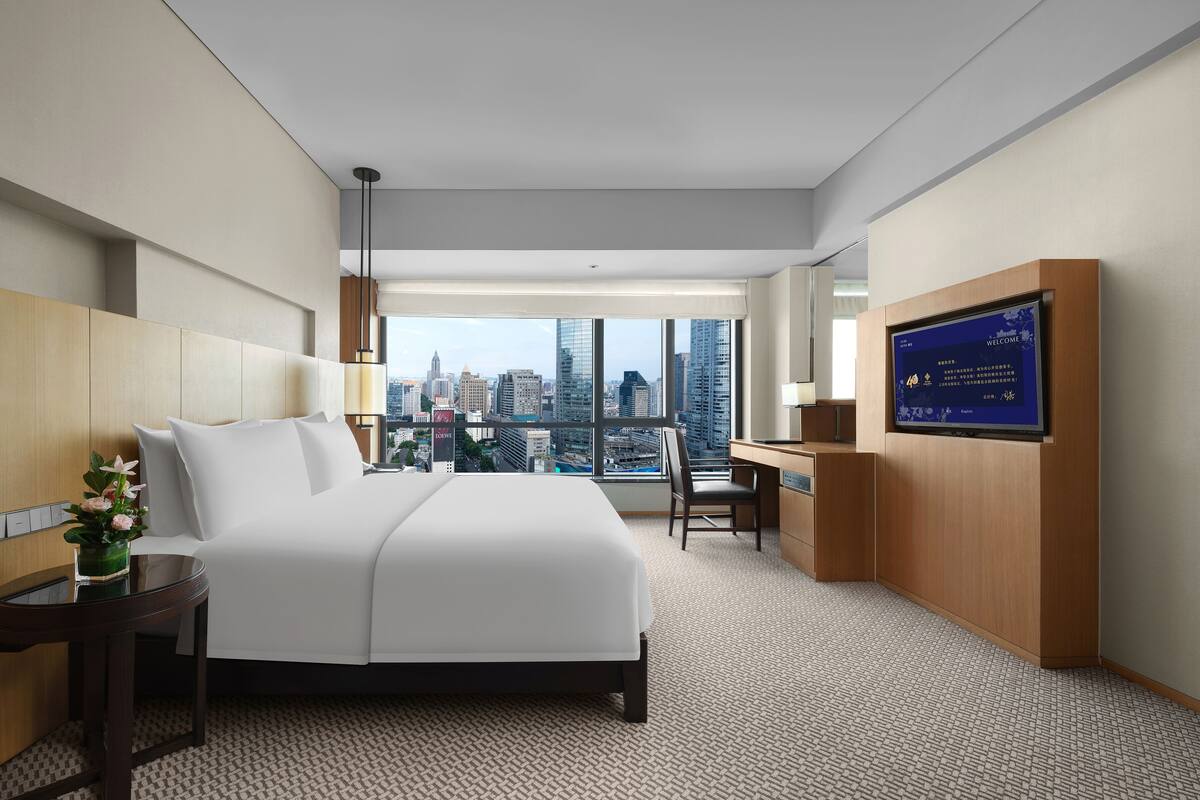 Une chambre d’hôtel avec un grand lit, un bureau, une télévision et une vue sur la ville.
