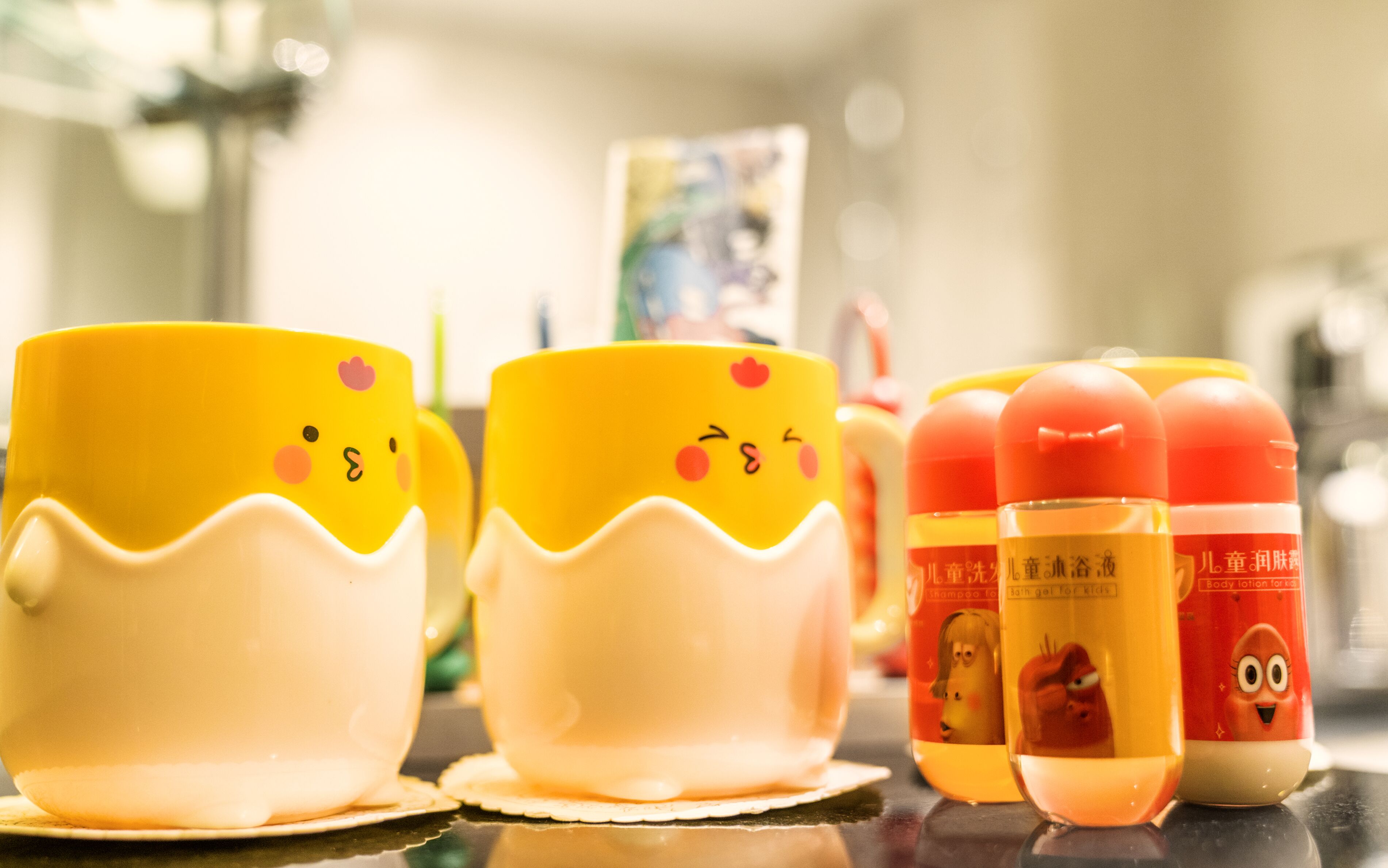 A row of yellow and white cups with cartoon faces, and two bottles of lotion with cartoon faces.