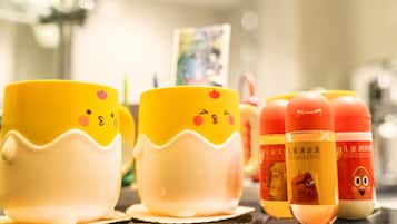 Una fila de tazas amarillas y blancas con caras de dibujos animados, y dos botellas de loción con rostros caricaturizados.