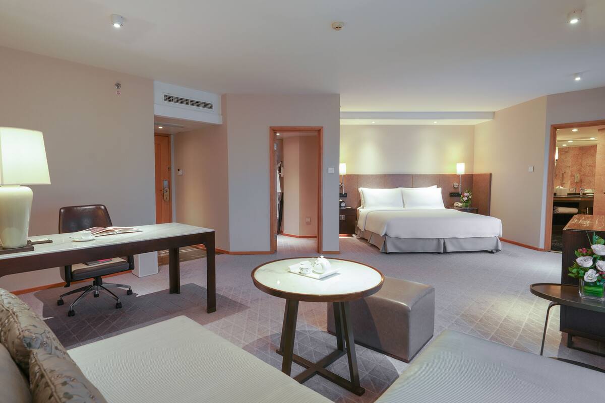 Une chambre d’hôtel comprenant un lit, un bureau, une chaise, une petite table et un canapé.