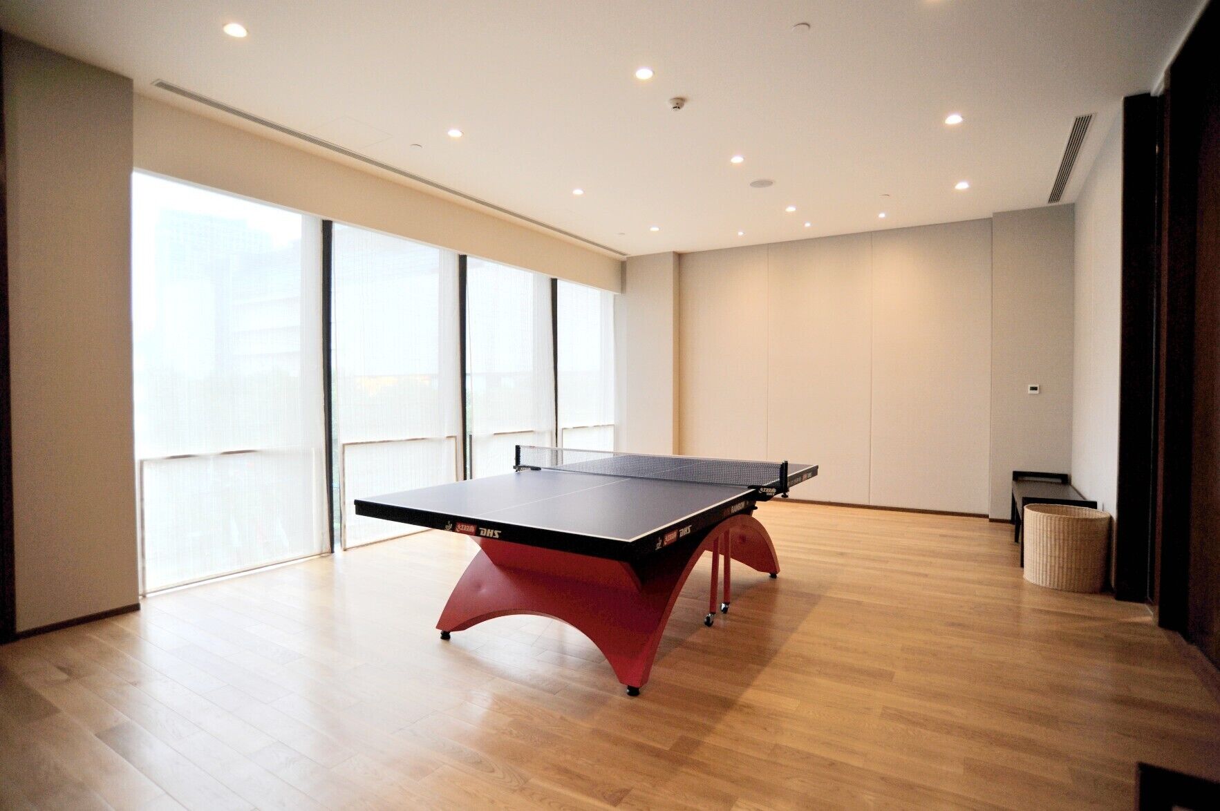 Una habitación amplia con mesa de ping-pong, ventanas grandes y un diseño moderno y limpio.