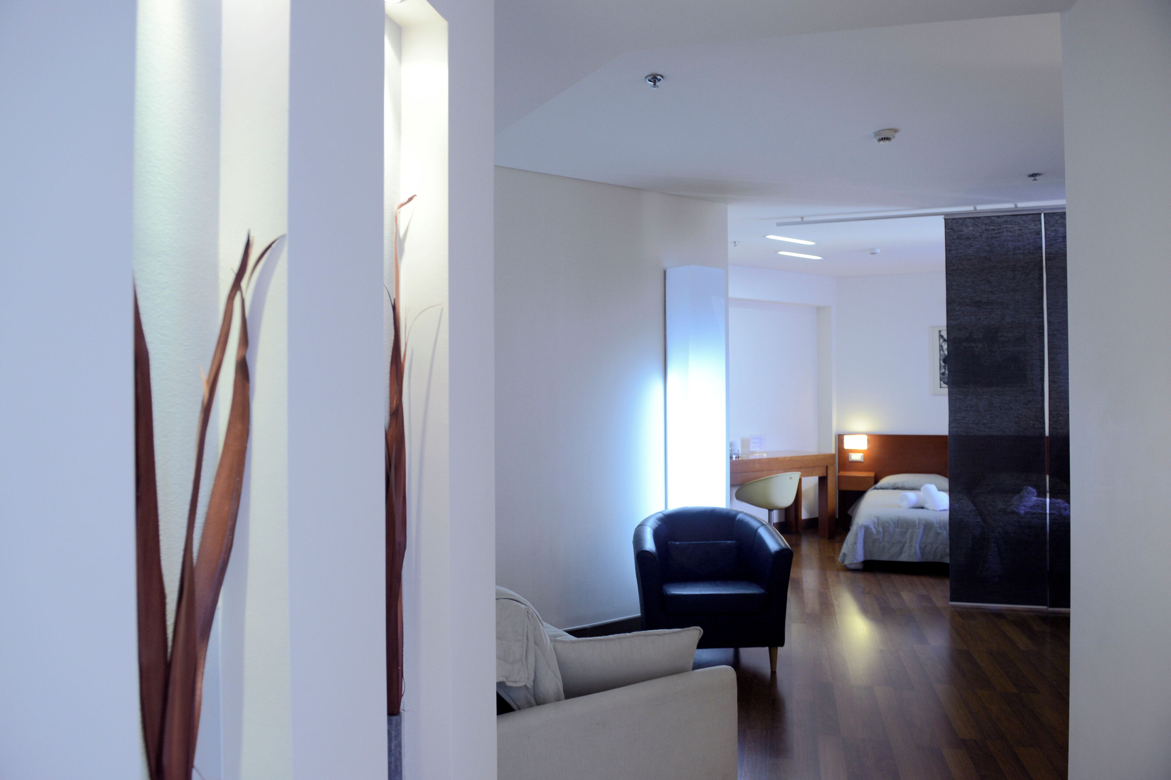 Ein modernes Hotelzimmer mit einem Bett, einer Sitzecke mit einem Sessel und einem großen Fenster.