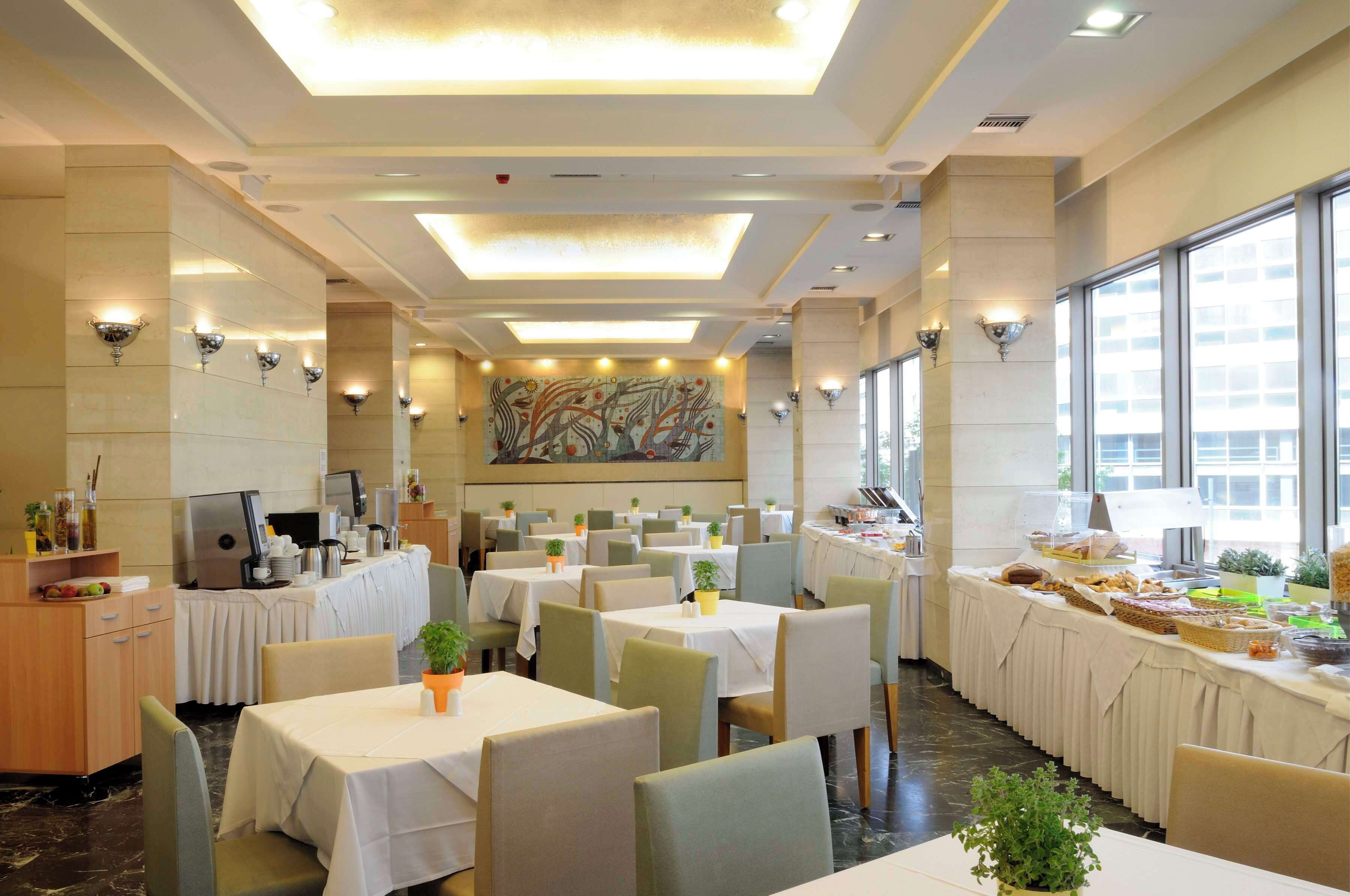 A hotel dining area with multiple tables, chairs, and a buffet setup.