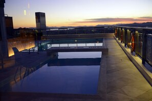 Una piscina en la azotea con vistas a la ciudad al atardecer.