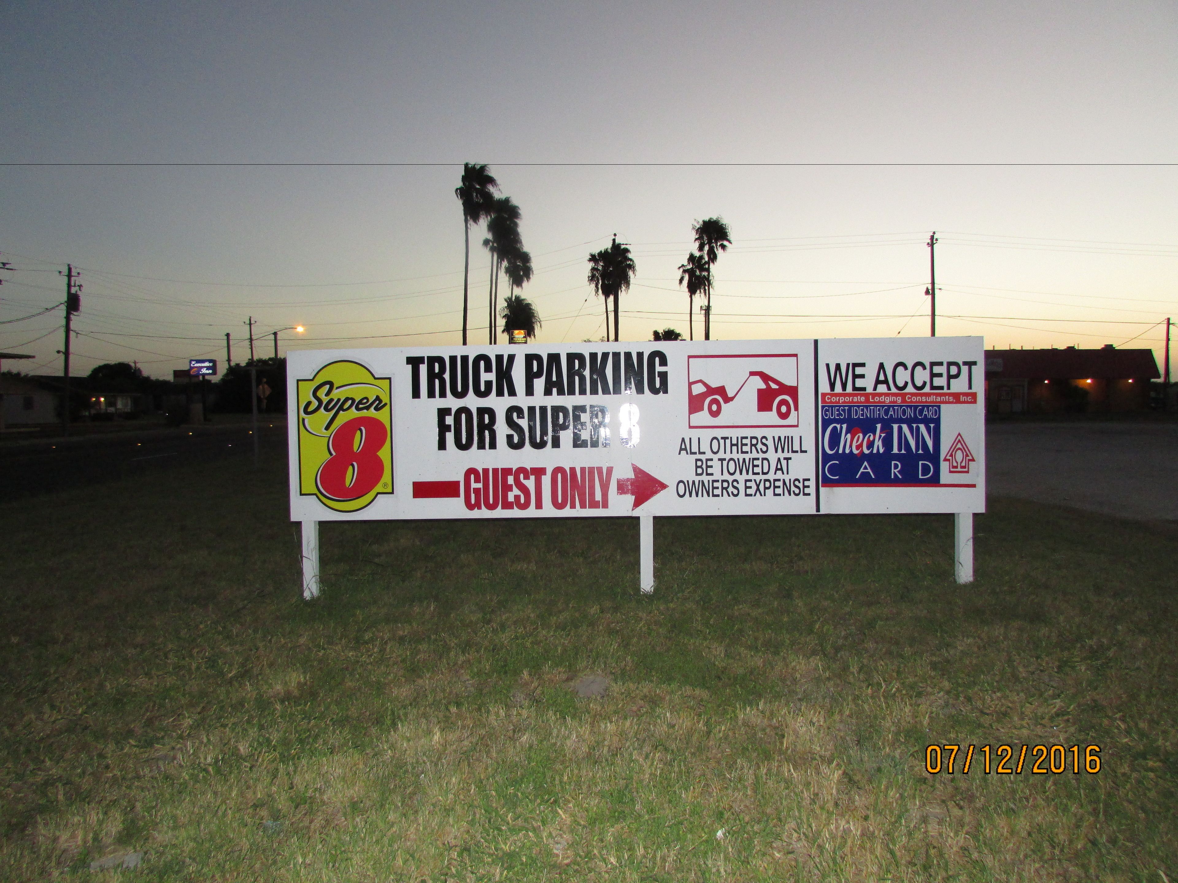 A sign indicating truck parking for Super 8 guests only, with a warning that all others will be towed at the owner's expense.