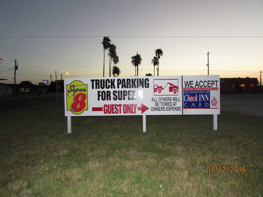 A sign indicating truck parking for Super 8 guests only, with a warning that all others will be towed at the owner's expense.