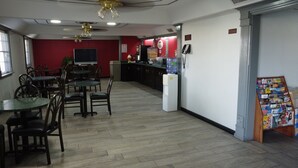 A restaurant with a red wall, a TV, and a water dispenser. - Super 8 by Wyndham Kingsville (Kingsville)