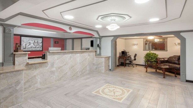 A spacious lobby with a reception desk, a seating area with a sofa and chairs, and a decorative floor pattern. - Super 8 by Wyndham Kingsville (Kingsville)