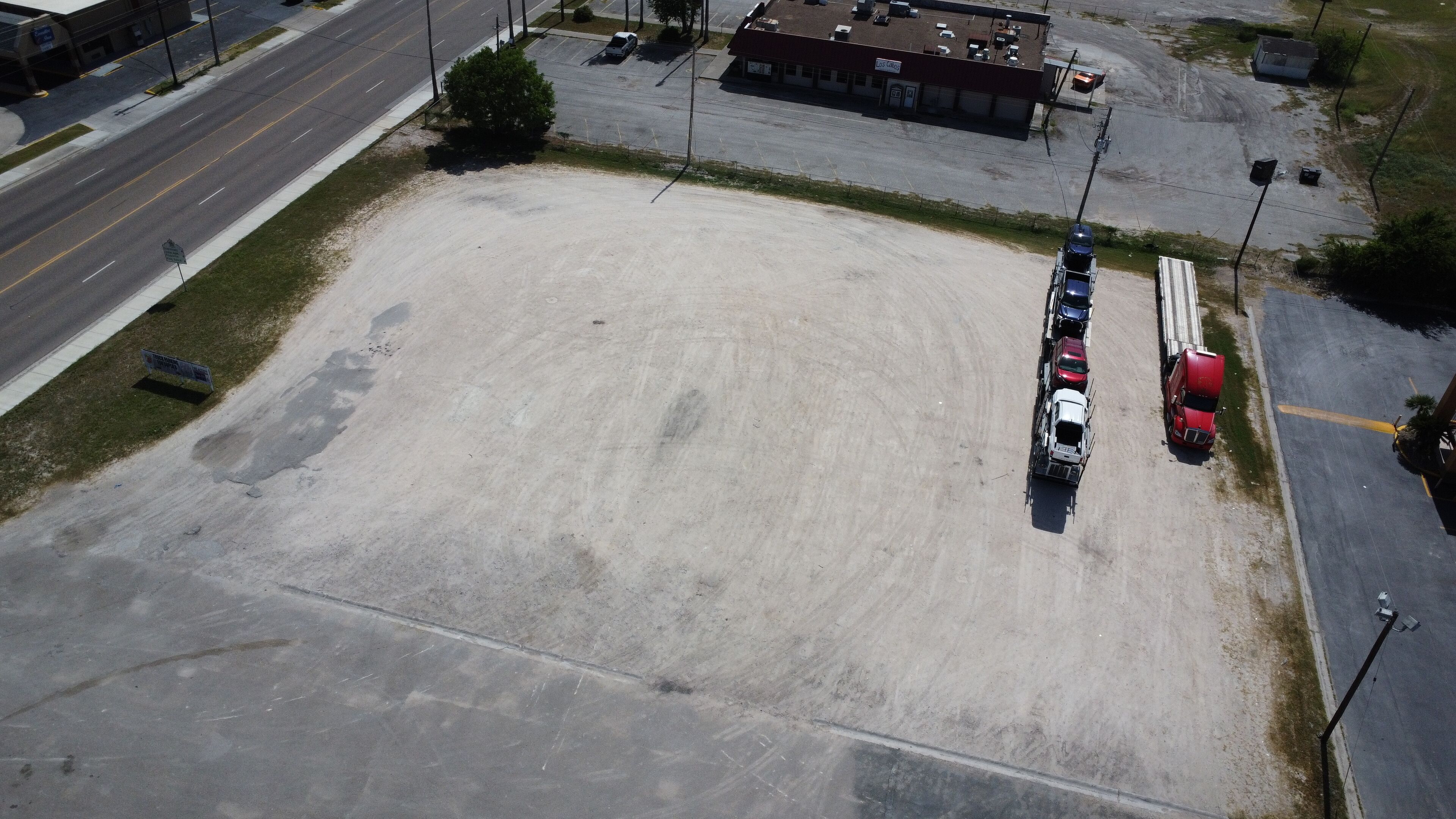 Um estacionamento vazio com alguns carros e um caminhão grande.