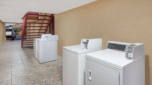 A laundry area with two washing machines and a dryer, a staircase, and a truck parked outside. - Super 8 by Wyndham Kingsville (Kingsville)