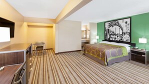 A hotel room with a bed, a desk, a chair, a nightstand, and a wall-mounted TV. - Super 8 by Wyndham Kingsville (Kingsville)