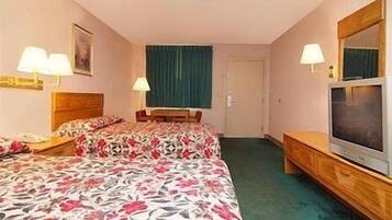 Ein Hotelzimmer mit zwei Betten, einem Fernseher, einem Schreibtisch und Lampen.