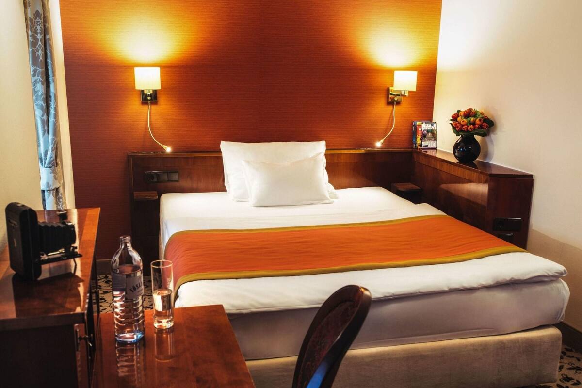Ein Hotelzimmer mit Bett, Nachttischen, einem Schreibtisch und einem Sessel.
