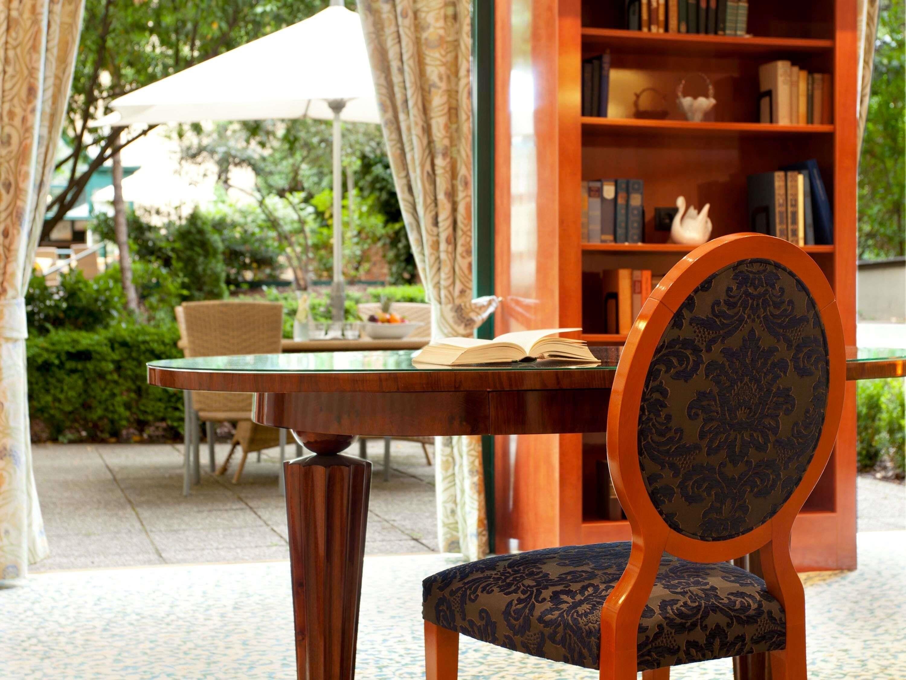 Een tafel met een boek, een stoel en een boekenkast op de achtergrond.