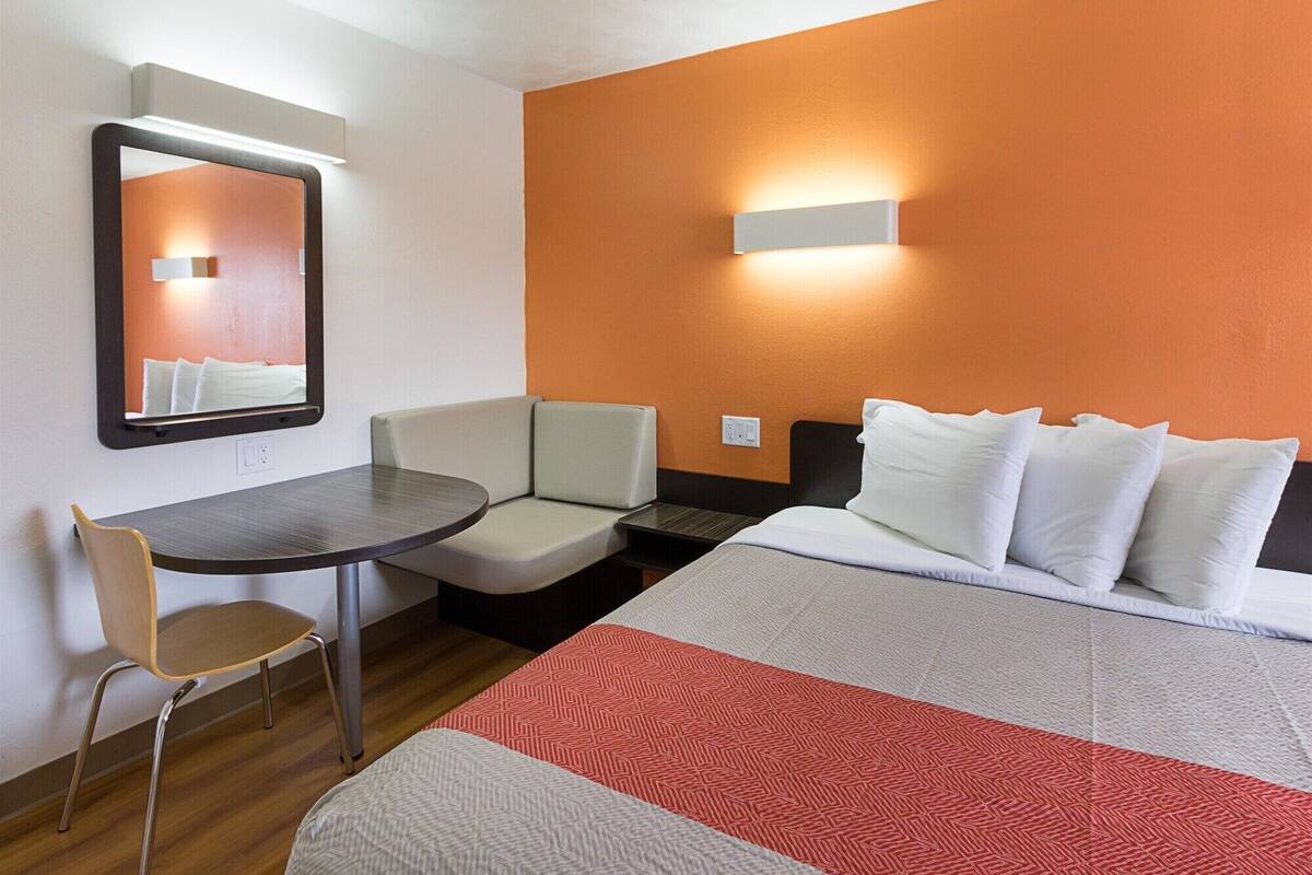 Hotellihuone, jossa on sänky, työpöytä, tuoli ja peili.