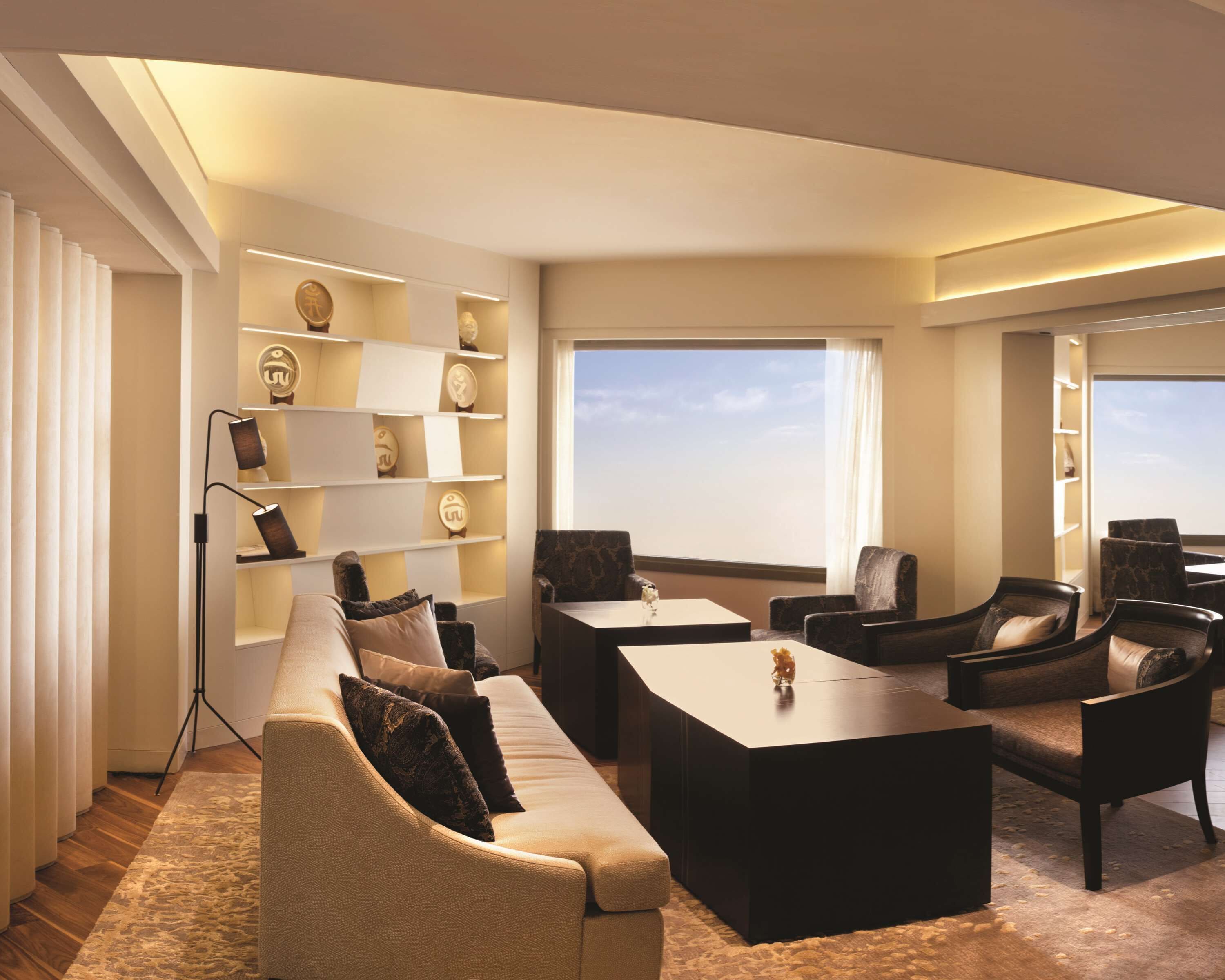 A modern living room with a sofa, chairs, a coffee table, and a bookshelf.