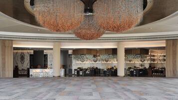 A spacious lobby with a patterned carpet, a reception desk, and a large decorative chandelier.