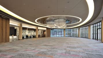 A spacious lobby with a marble reception desk, a large chandelier, and a view through the glass doors.