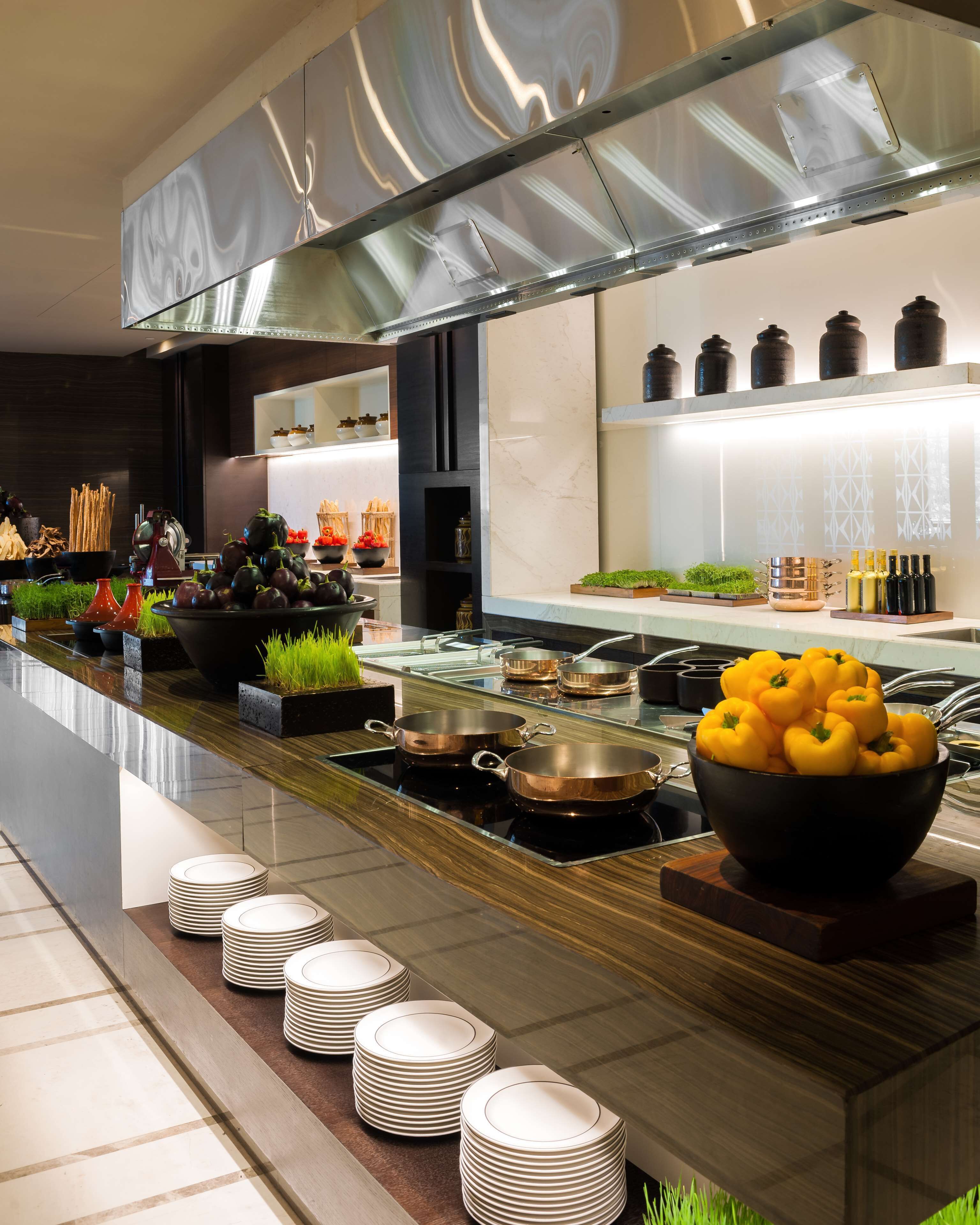 A modern kitchen with stainless steel appliances, a long counter, and neatly stacked plates.