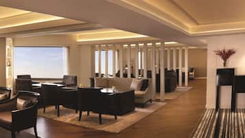 A modern living room with a sofa, chairs, and a coffee table. There is a large window with a view, and a decorative vase on a console table.