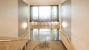 Una escalera con barandilla, una ventana con cortinas y una pared con textura.