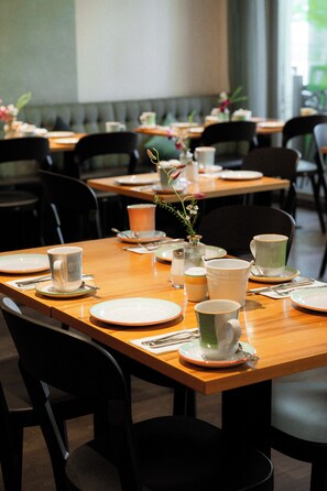 Un ristorante con tavoli apparecchiati per la cena, sedie e un vaso di fiori sul tavolo.