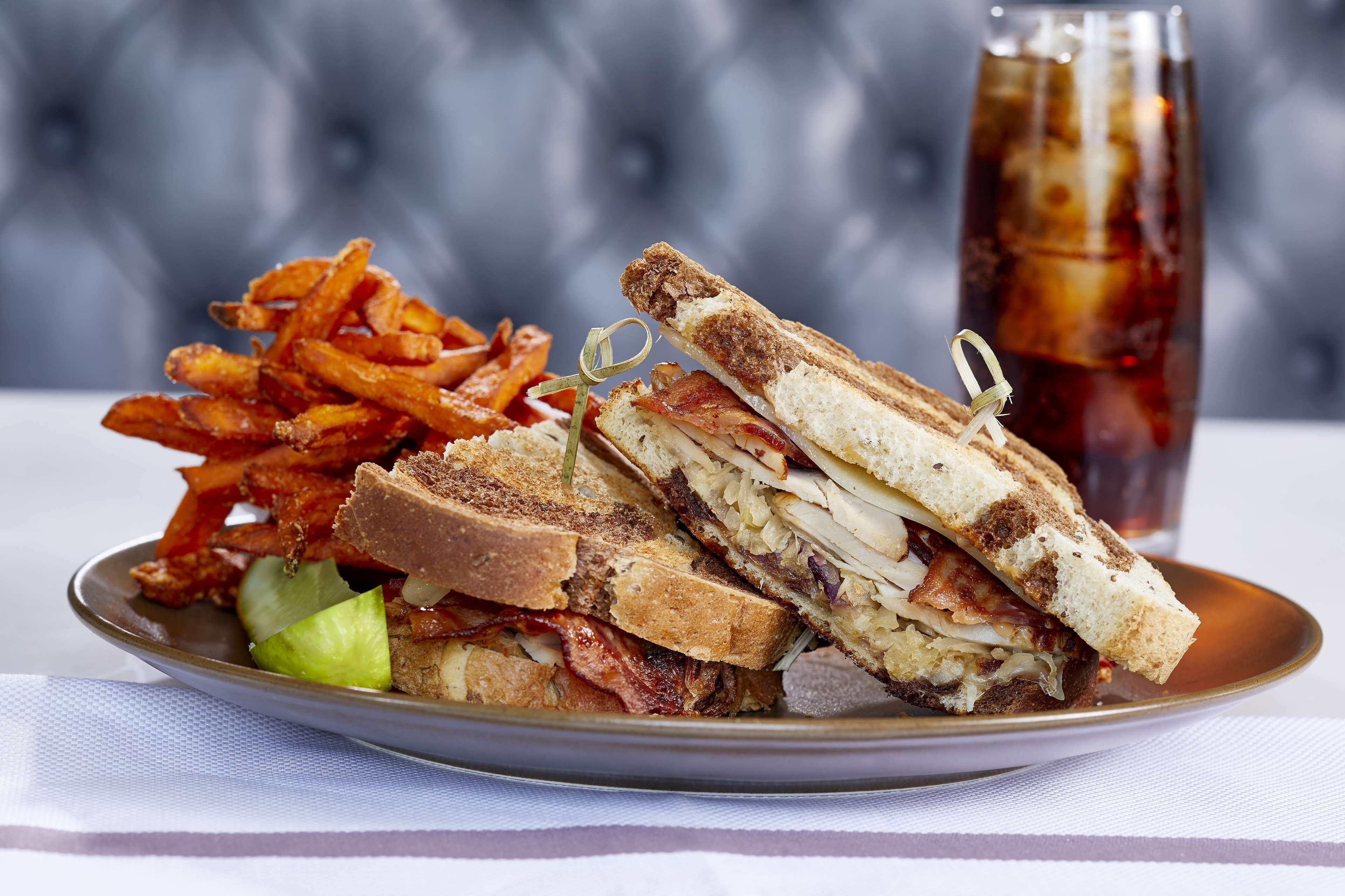 A plate with a sandwich, fries, and a drink.