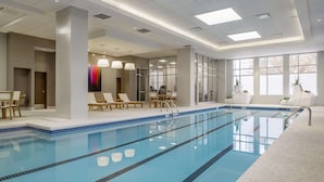 An indoor swimming pool with clear lanes, lounge chairs, and a seating area with potted plants. - Hyatt Centric Midtown Atlanta (Atlanta)