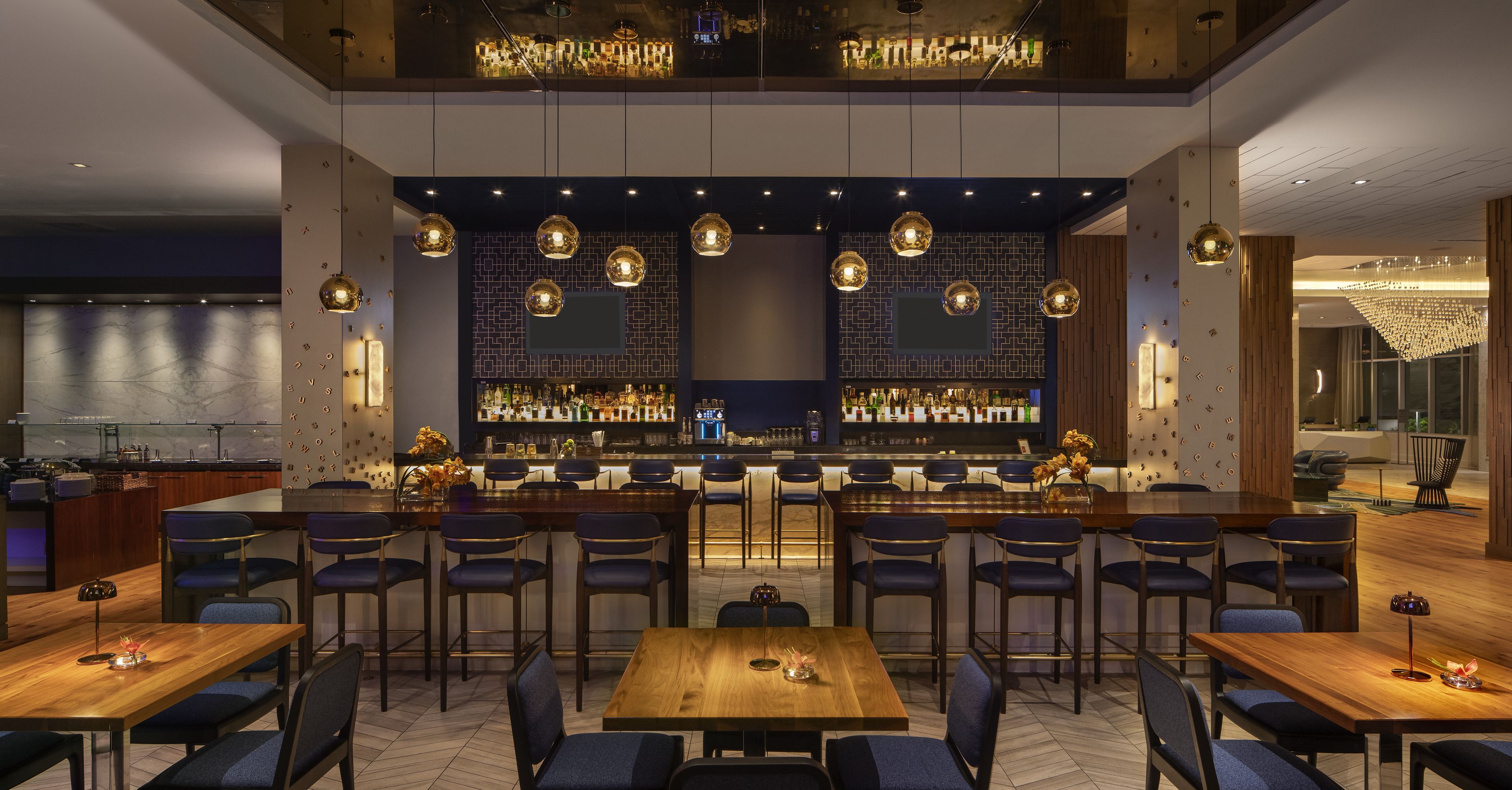 Zona de bar con diversas opciones de asientos, incluyendo taburetes y mesas, y una barra con una variedad de botellas.